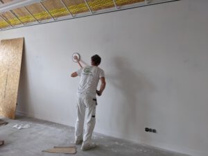 Foto van Harry die aan een gipsplaat aan het schuren is.